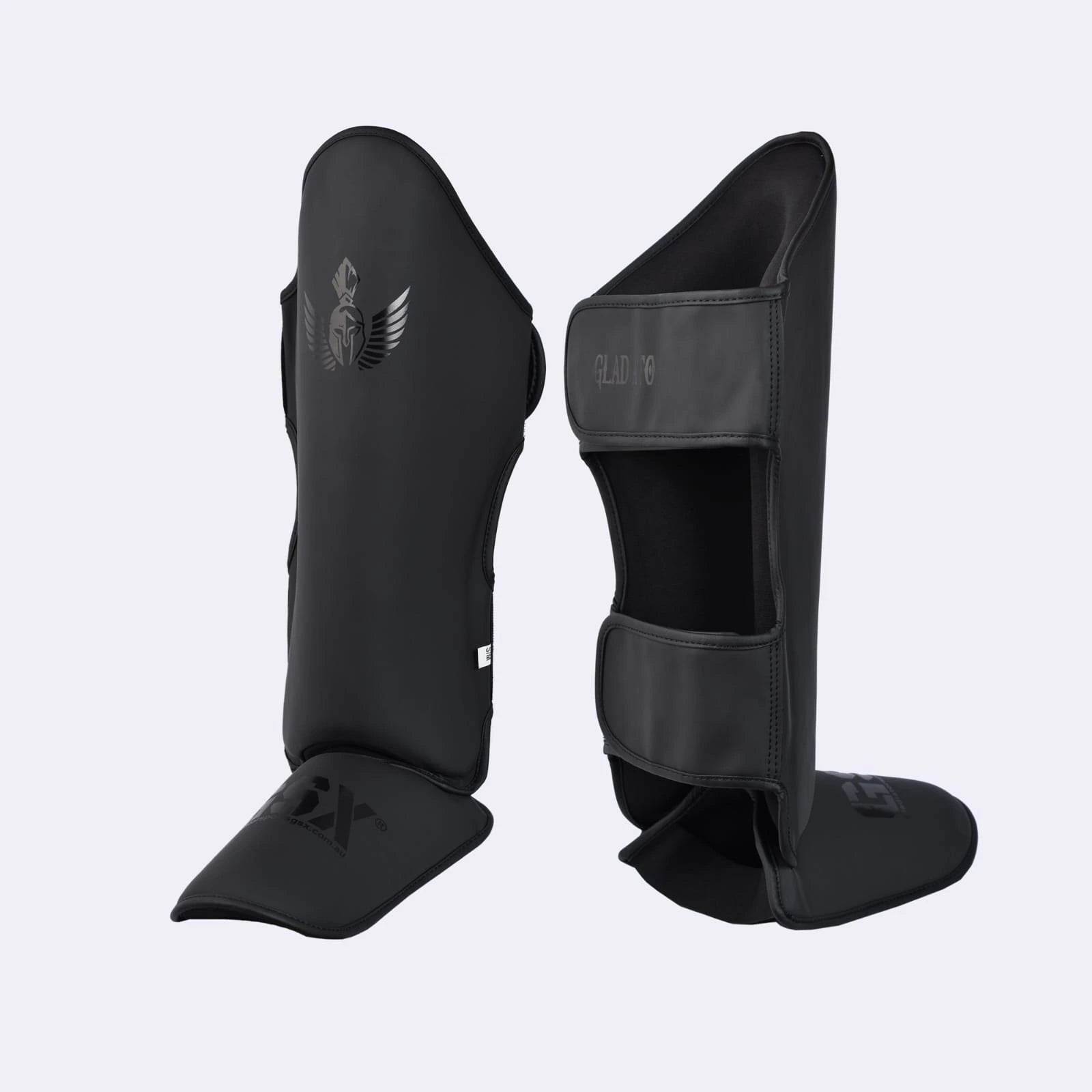 Pair of black GSX Gladiator martial arts shin guards with a Spartan helmet logo, shown from the front and back.