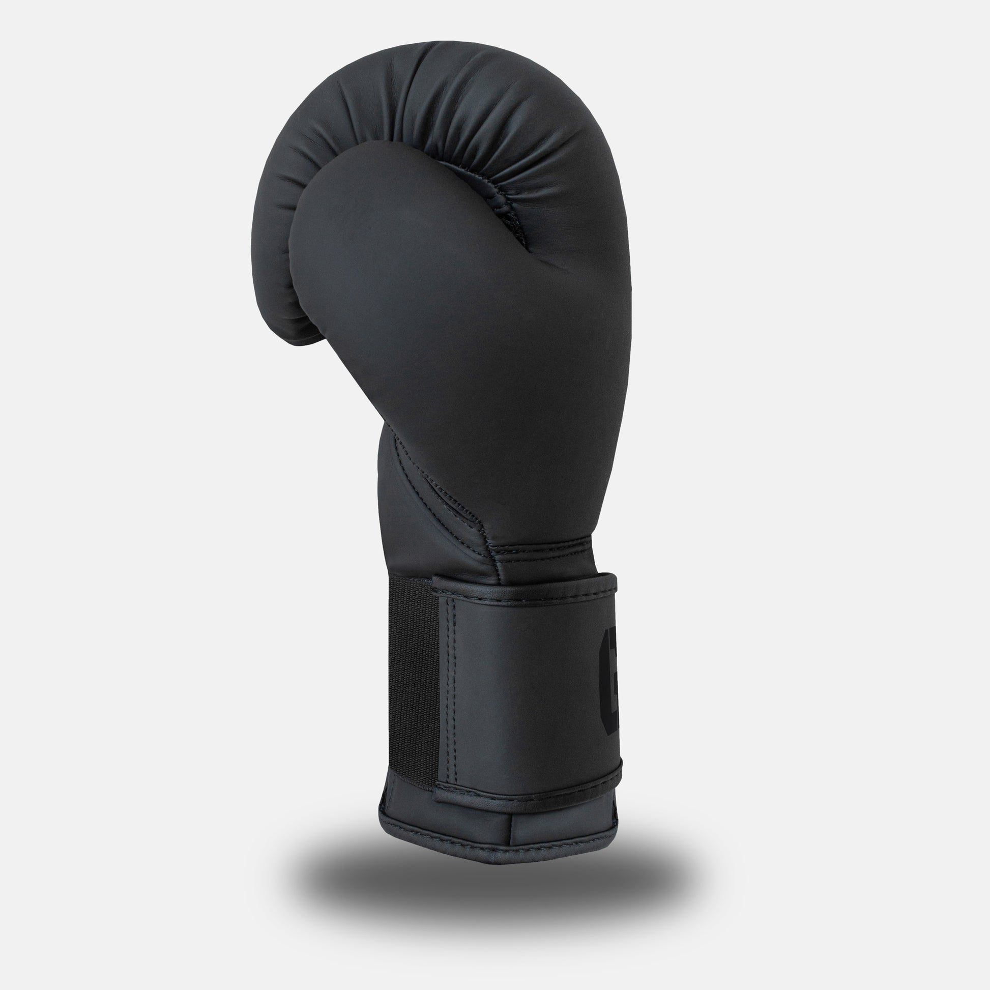 Side profile of GSX Black on black boxing glove featuring smooth contour padding and a reinforced wrist strap
